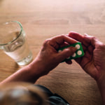 Unrecognizable senior woman taking a pill with a glass of water.