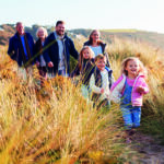 Multi-Generation Family Walking Along Path Through Sand Dunes Together