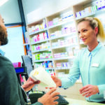 Pharmacist giving medicine package to customer